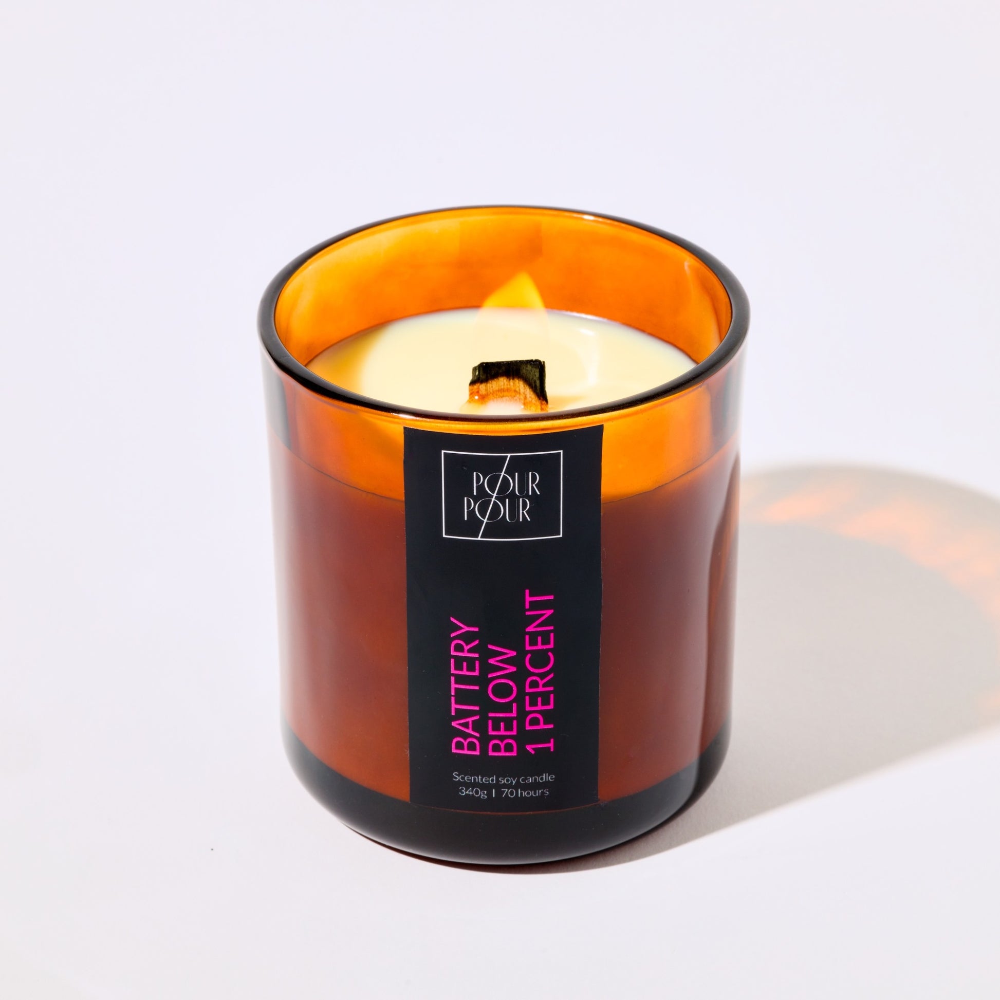 Candle in an amber glass jar with a label on a white background