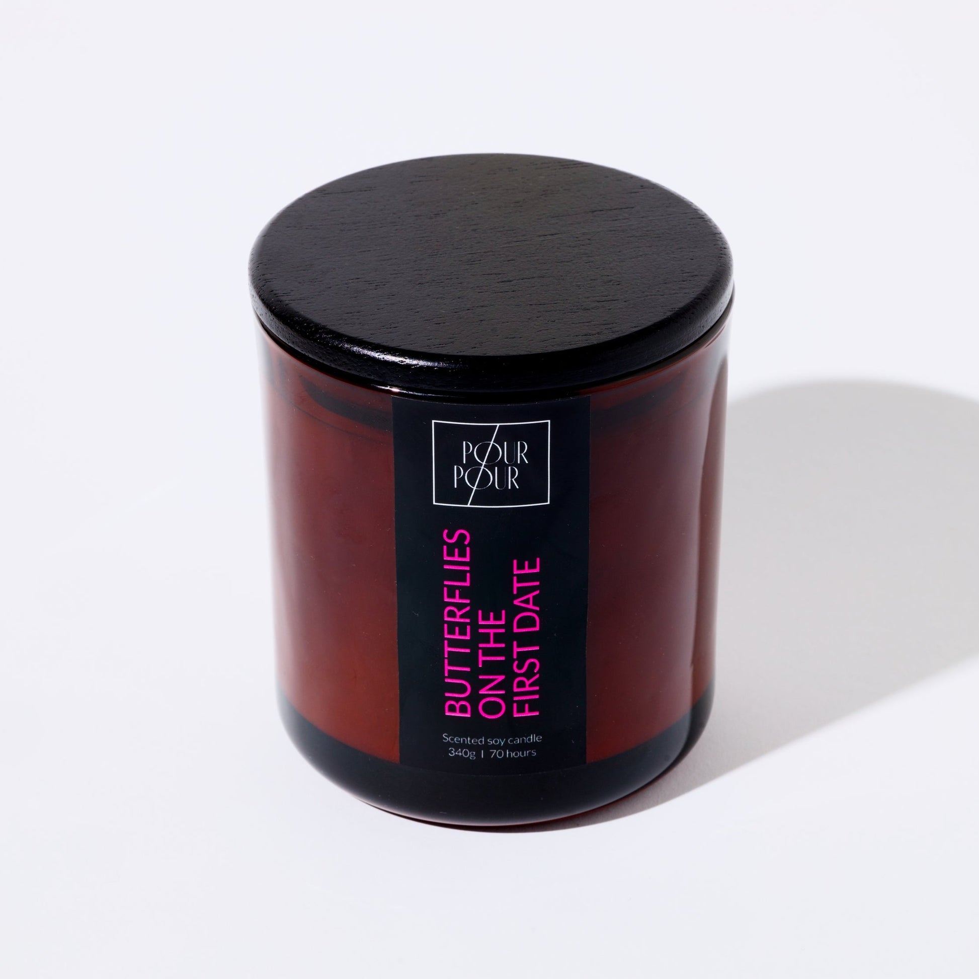 Candle jar with black lid and visible branding on a white background