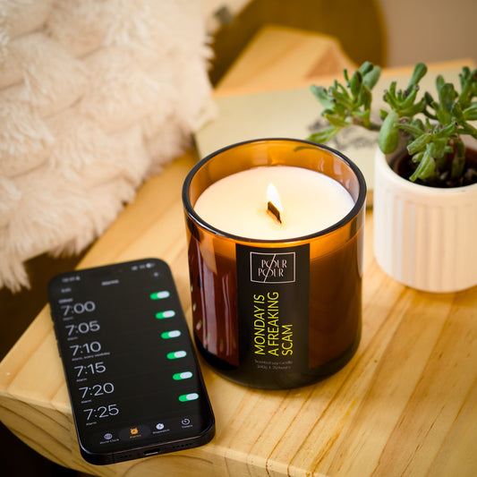 Candle with a smartphone displaying a timer and a plant on a wooden surface.