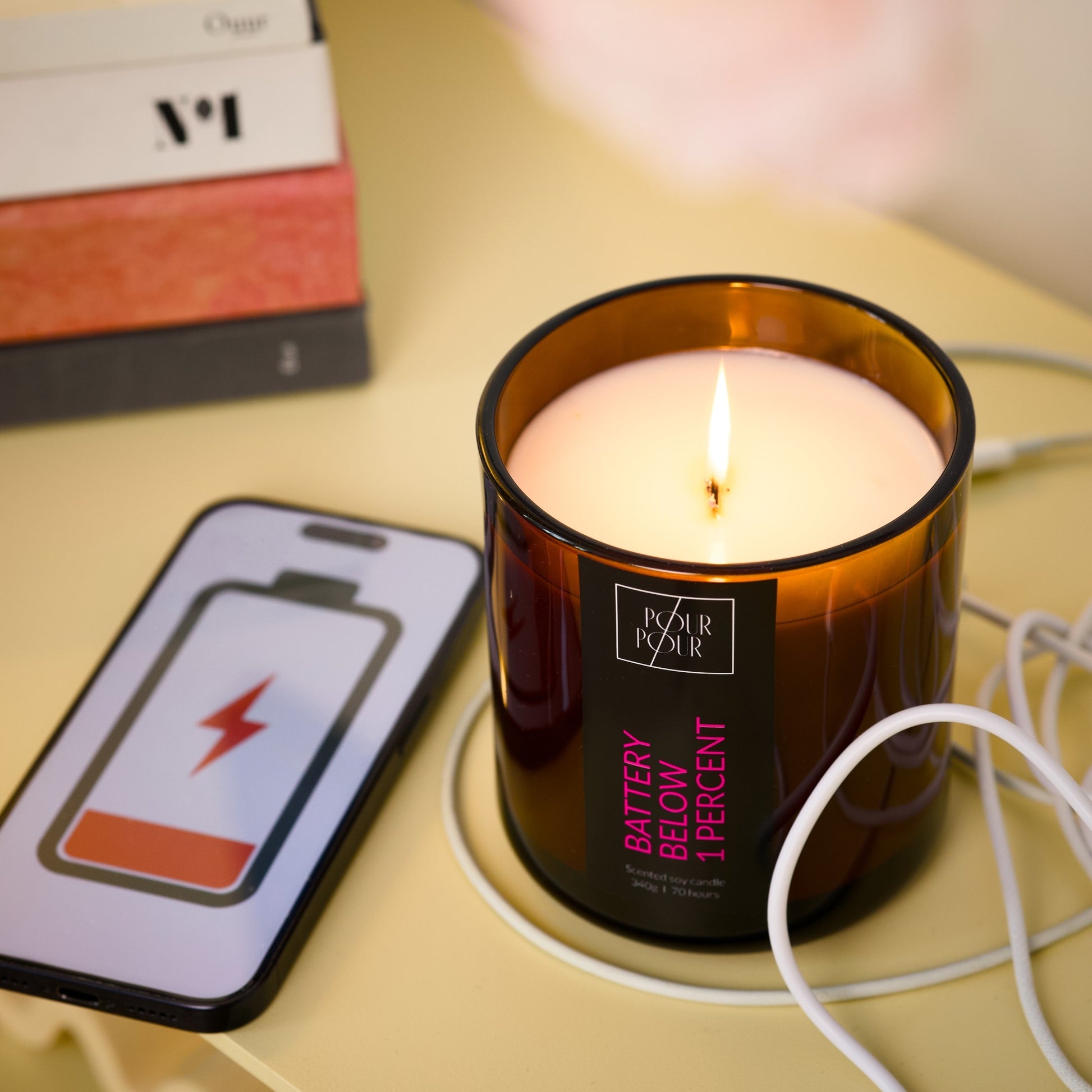 Candle labeled 'Battery Below 1 Percent' with a smartphone showing battery icon on a table.
