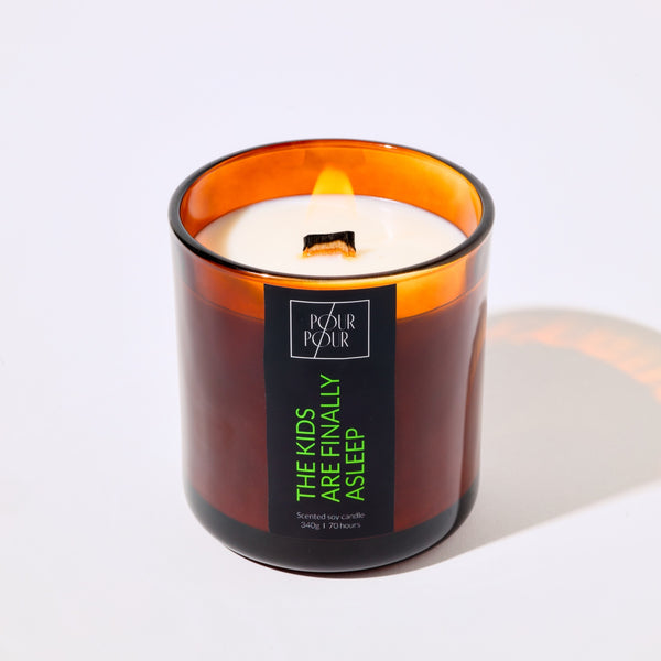 Candle in an amber glass jar with a visible label on a white background